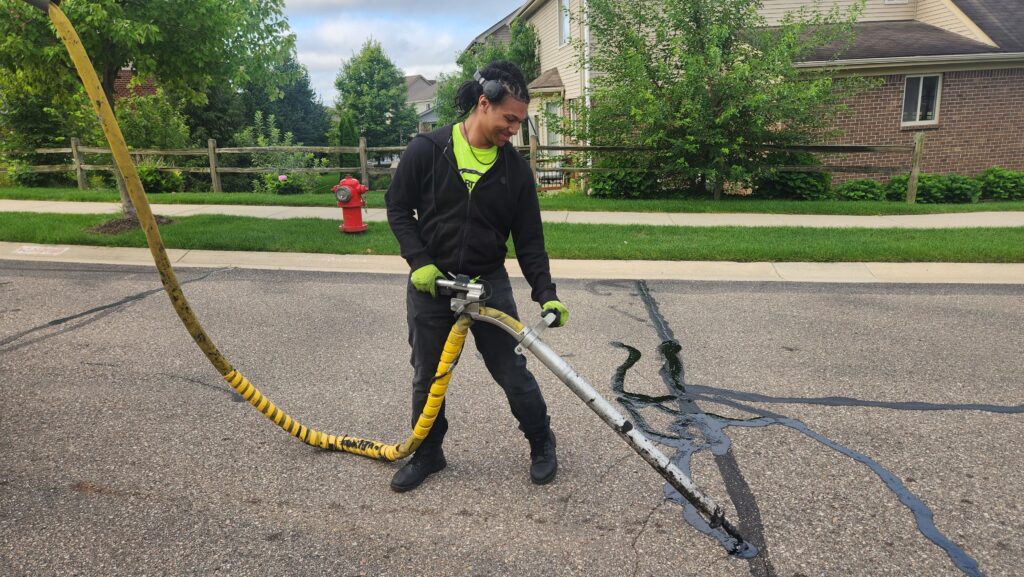 Man filling asphalt cracks with hot rubber in Commerce Twp, Michigan