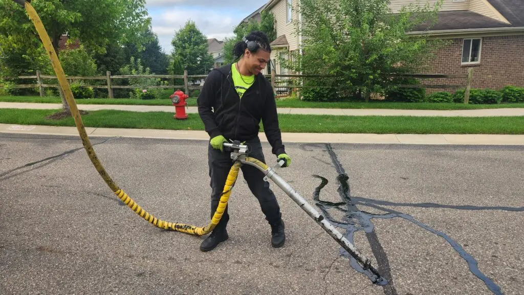 Man filling asphalt cracks with hot rubber in Commerce Twp, Michigan